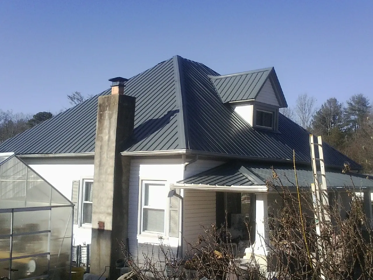 Dark blue standing seam metal roof on a white farmhouse with dormer — Slate & Tile Roof Repair by Roofing Brothers in Richwood