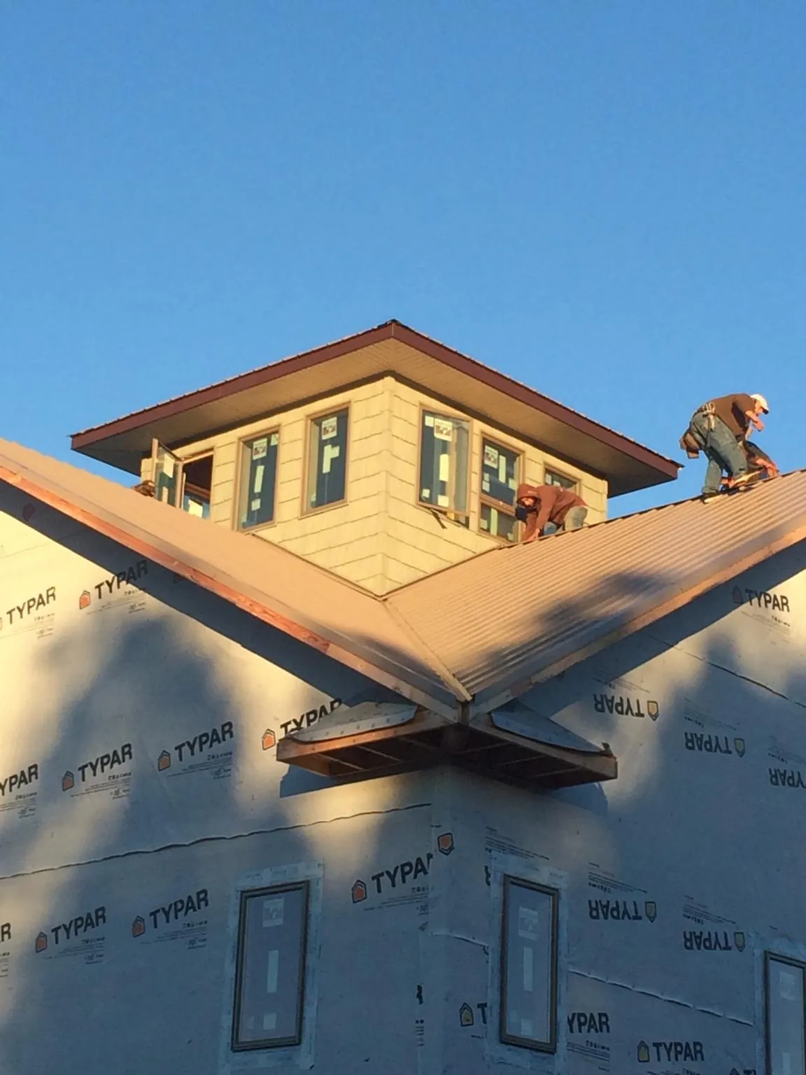 Roofers working around a rooftop cupola on a new metal roof at sunset — Roof Waterproofing in Richwood by Roofing Brothers